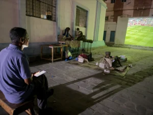 Adel-Mohsen-watches-the-opening-match-of-the-World-Cup-on-a-giant-public-screen-in-Mukalla-while-tak.webp