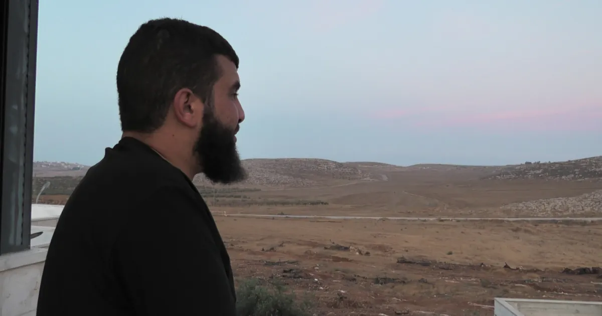 Bilal-Abu-Alia-is-standing-in-his-balcony-looking-at-his-confiscated-land-photo-by-Mutasim-Abu-Alia.webp