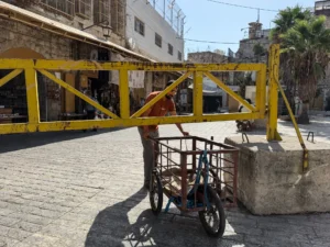 A-Palestinian-man-tries-to-pass-under-an-iron-gate-in-Hebron-as-Israel-tightens-the-movement-there-P.webp