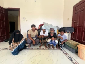 Saeed-second-from-right-and-his-brother-Mohammed-center-pose-with-their-families-behind-a-pile-of-ba.webp